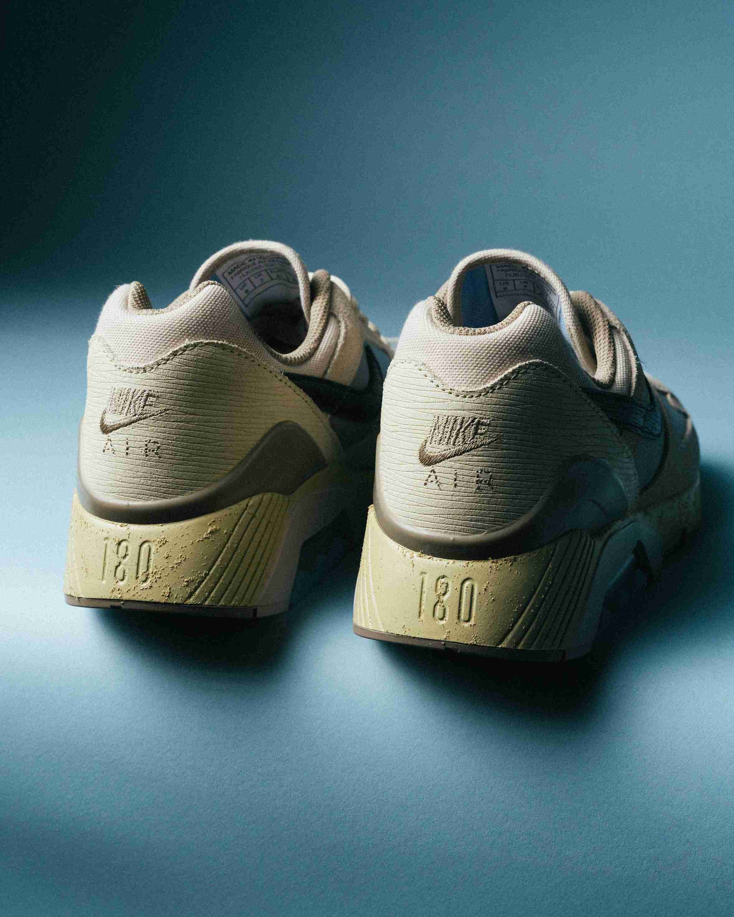 Paire de sneakers beige et bleu clair posée sur un fond bleu, vue de trois quarts avec mise en avant des formes et détails du modèle.